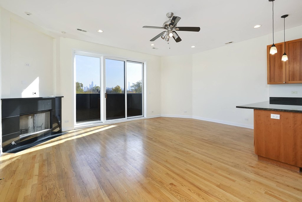 an empty living room with a fireplace and wood flooring