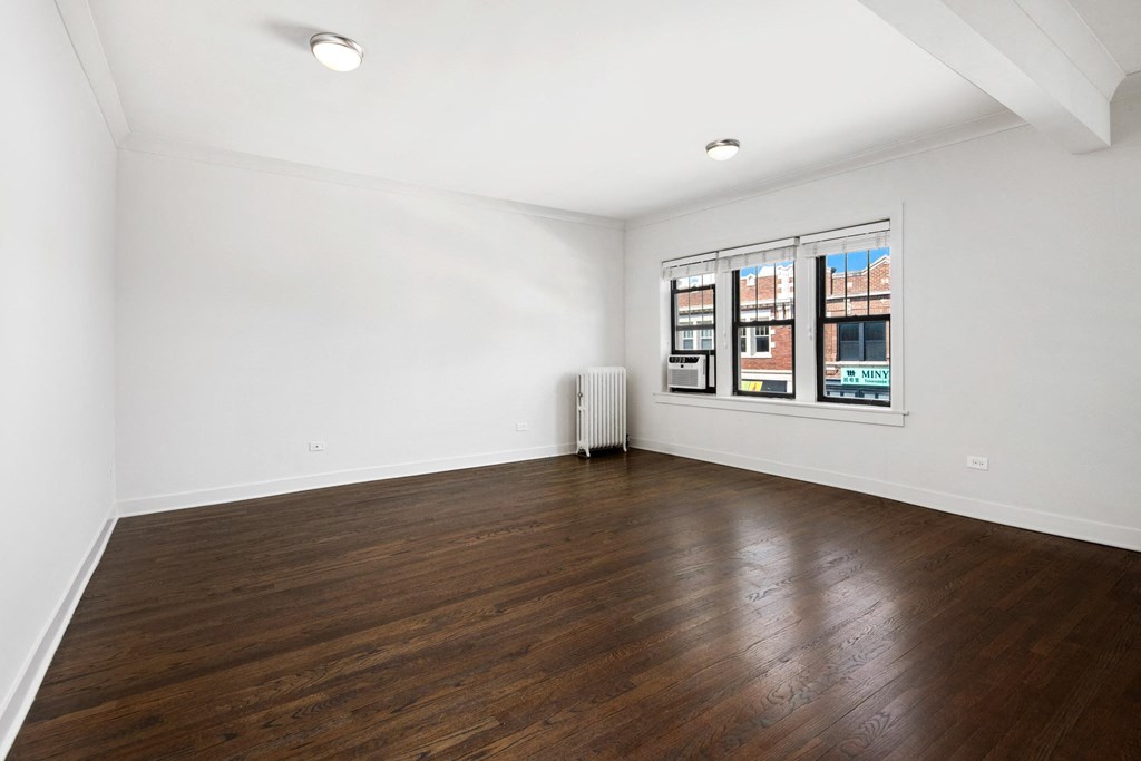 an empty living room with wood floors and white walls