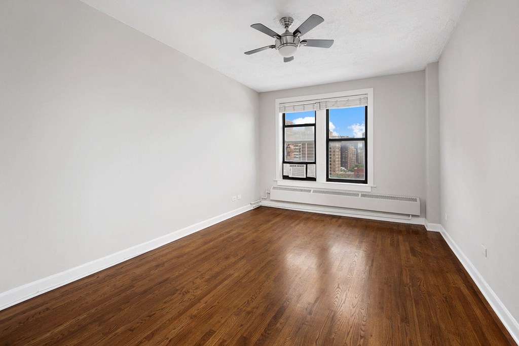 an empty living room with wood floors and a window