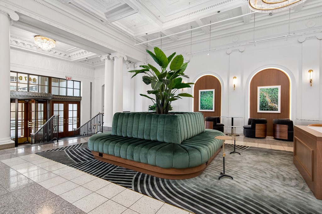 the lobby of a hotel with a green couch and a large plant