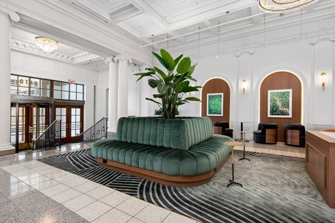 the lobby of a hotel with a green couch and a large plant