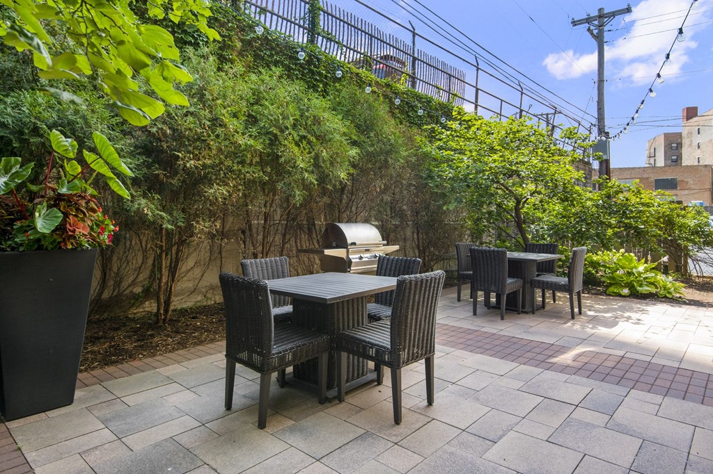a patio with a table and chairs and a grill