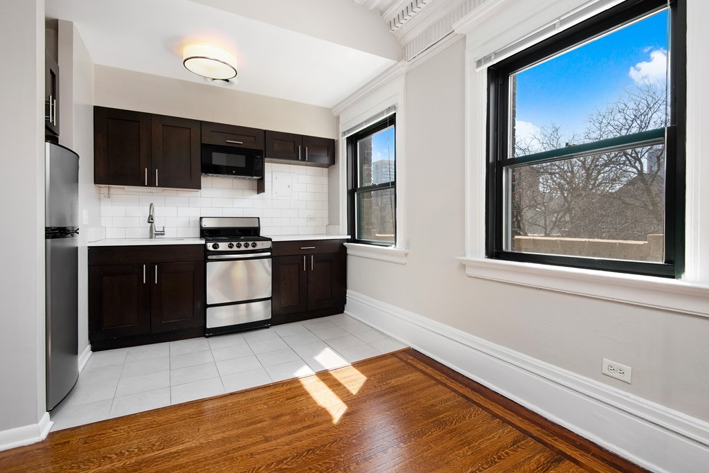 A kitchen with white tiles and wooden floors.