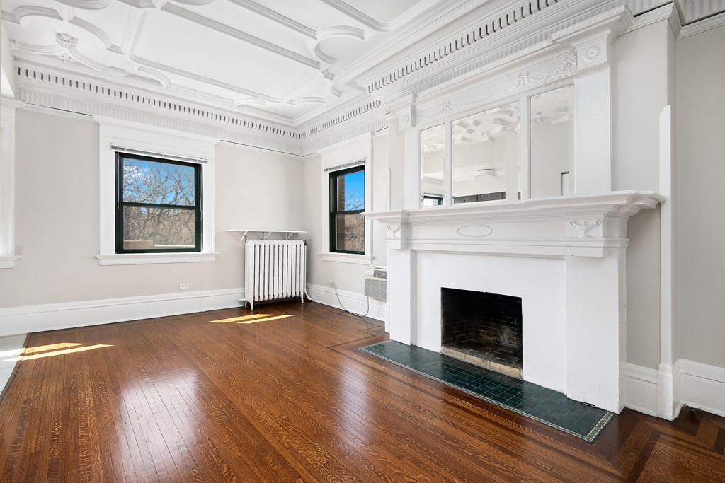 A large, empty room with a fireplace and wood flooring.