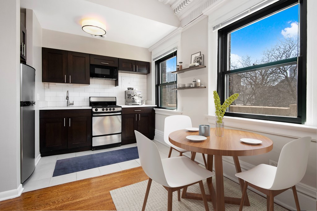 A kitchen with a table and chairs by a window.