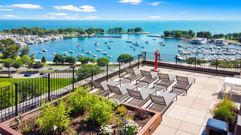 a view of a marina with boats in the water and a deck with chairs