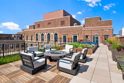 a patio with chairs and a fire pit on the roof of a building
