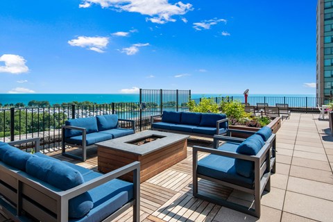 a lounge area with blue couches and a fire pit overlooking the ocean