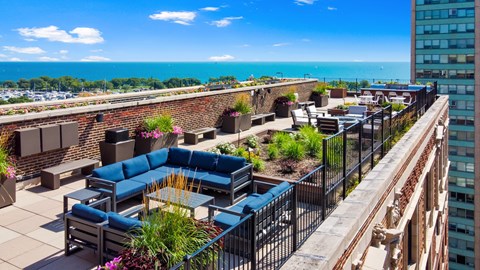 a rooftop patio with blue couches and a view of the ocean