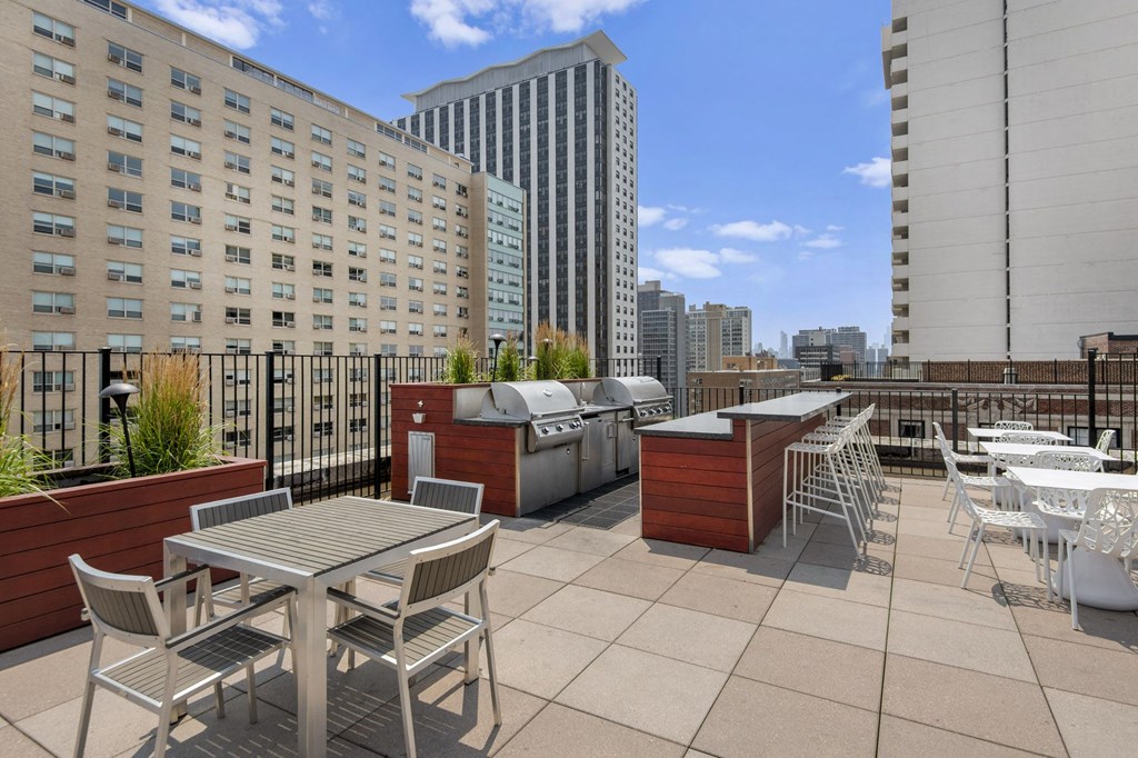 a rooftop patio with tables and chairs and buildings in the background