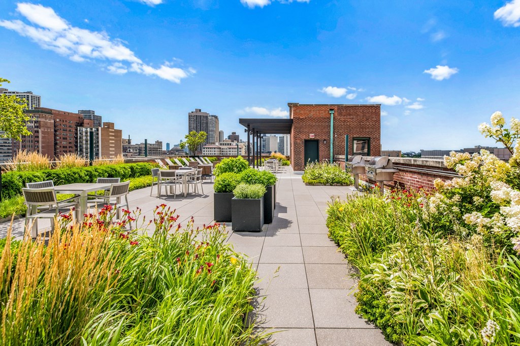 a rooftop patio with tables and chairs and a city in the background