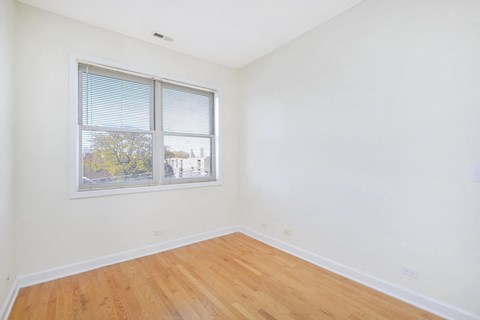a bedroom with a large window and a wooden floor