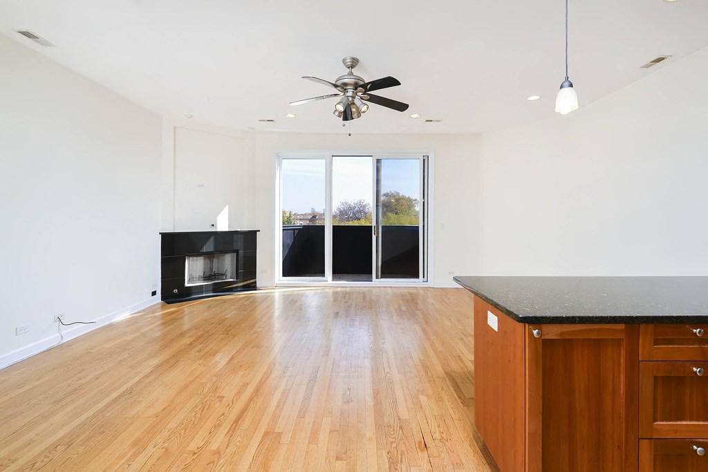 an empty living room with a ceiling fan and a fireplace
