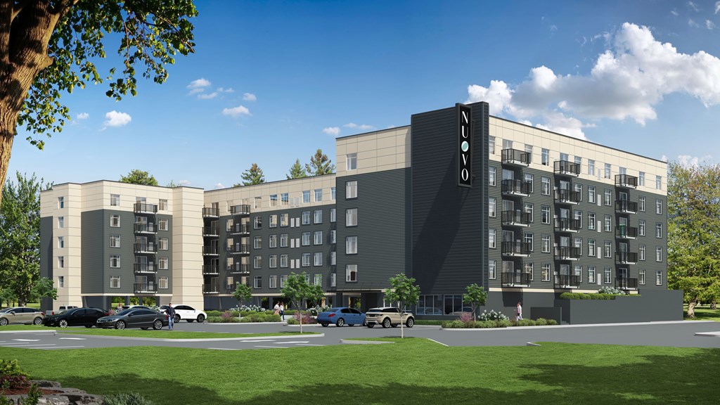A modern apartment building with a parking lot in front.
