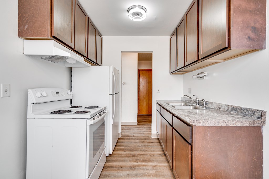 A kitchen with white appliances and brown cabinets.