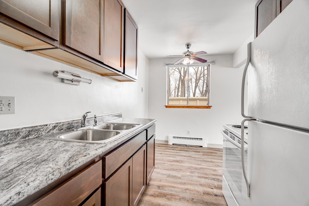 A kitchen with a marble countertop and a white refrigerator.