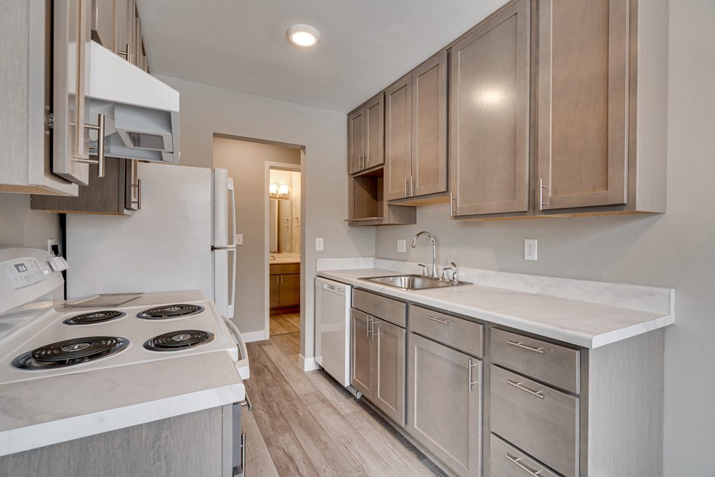 A kitchen with a white stove top oven and a white counter top.