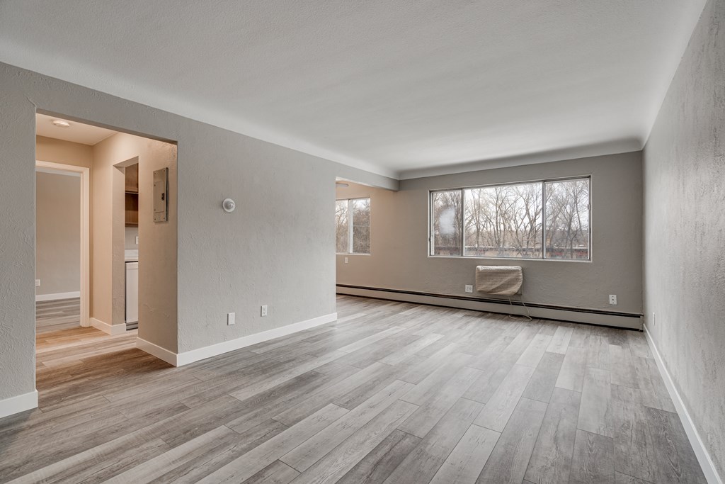 A room with wooden flooring and a window with a view of trees.