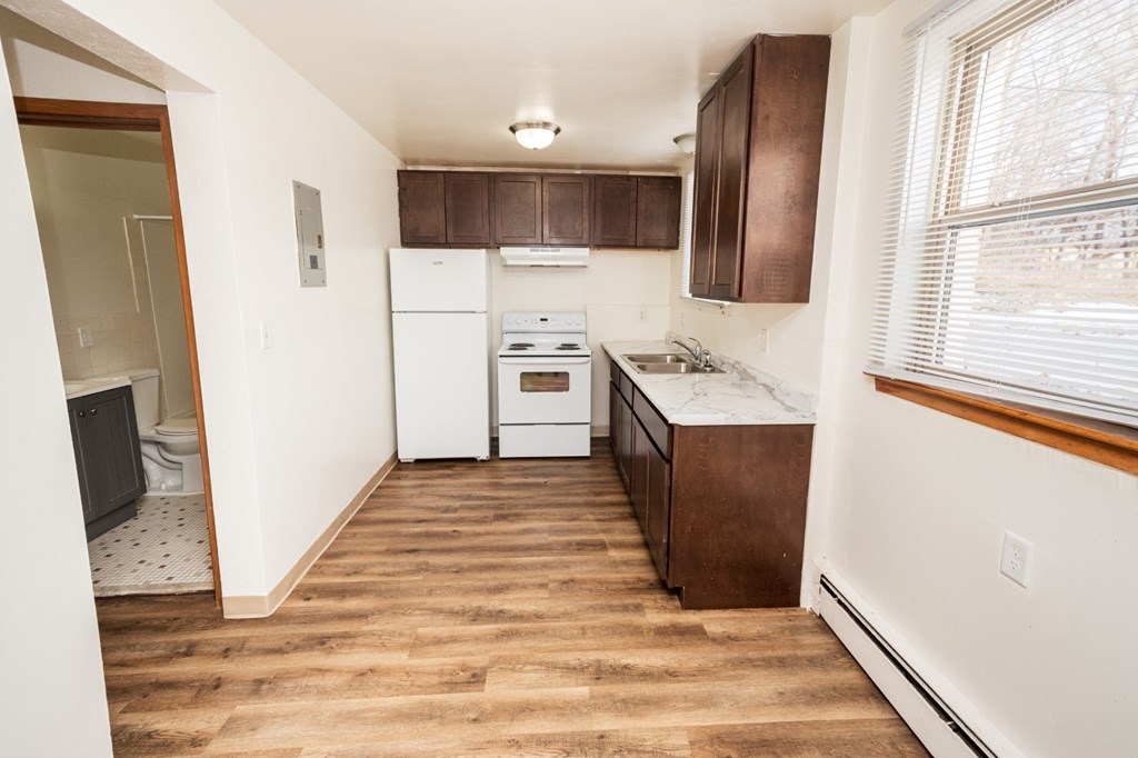 A kitchen with white appliances and brown cabinets.