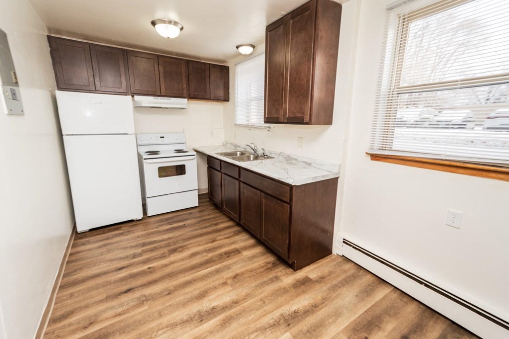A kitchen with white appliances and brown cabinets.