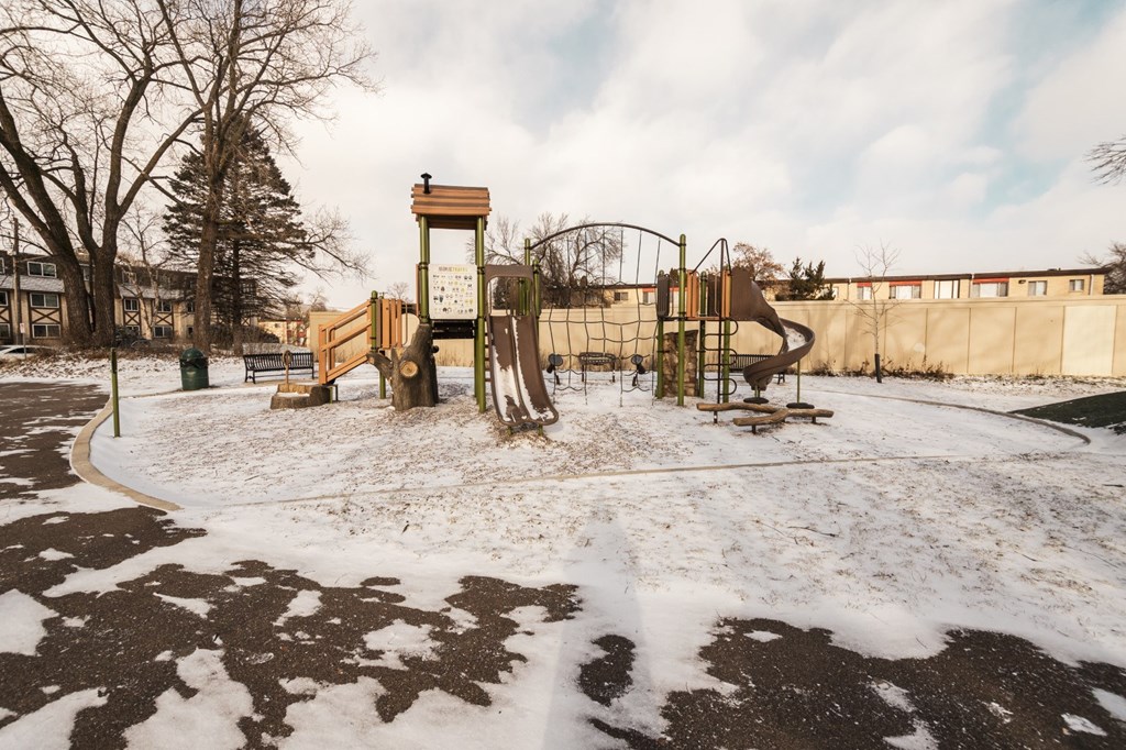 A playground with a wooden swing set and a climbing frame.