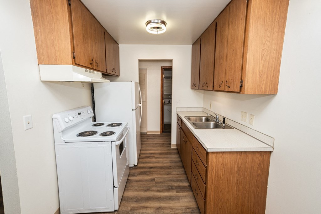 A kitchen with a white stove and wooden cabinets.