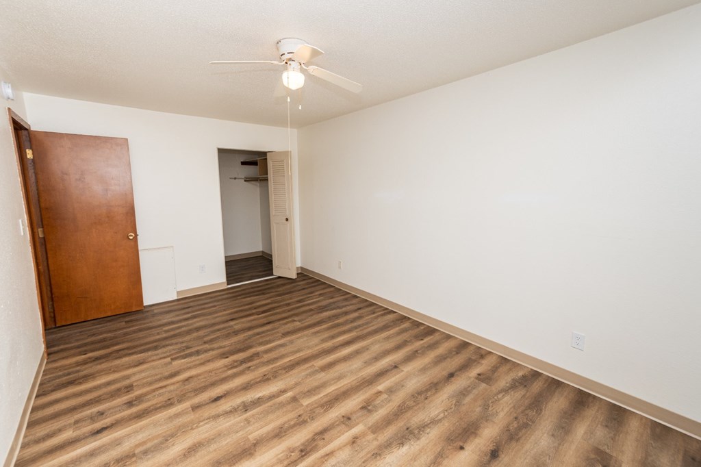 A room with a ceiling fan and wooden flooring.