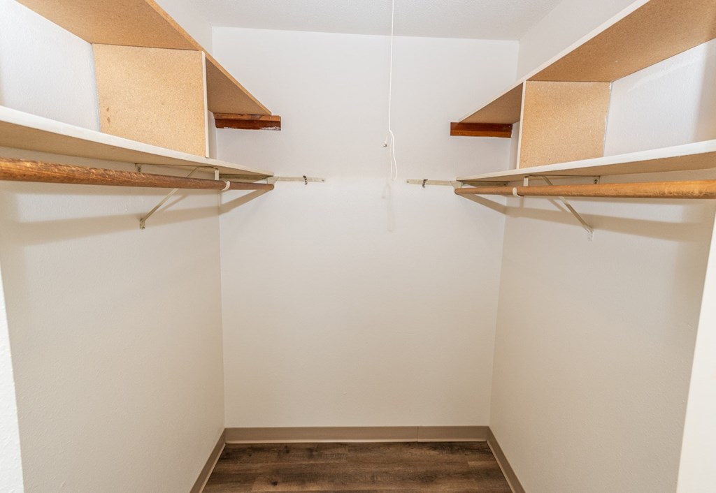 Empty white walk in closet with shelves.