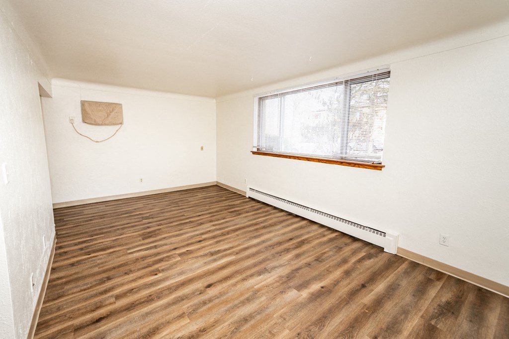 A room with wooden flooring and a window with blinds.