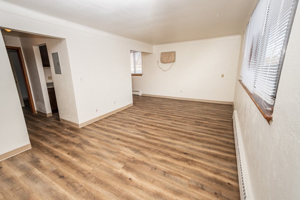 A room with wooden flooring and a window with blinds.