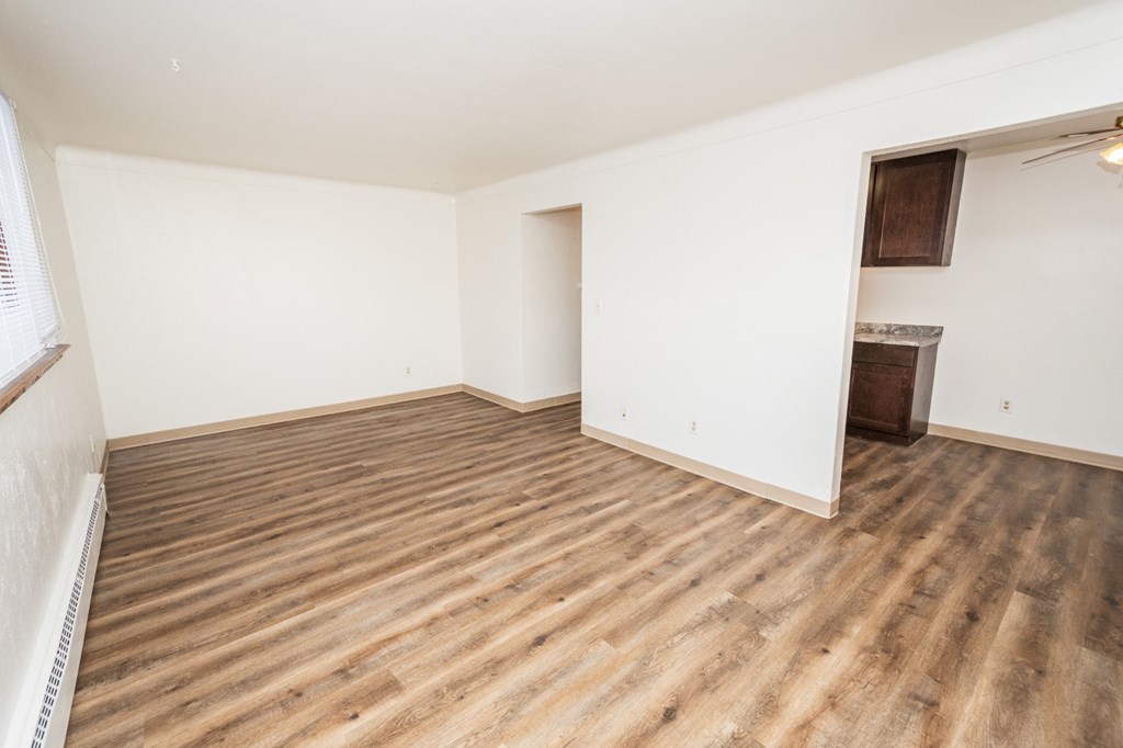 Empty room with wooden flooring and white walls.