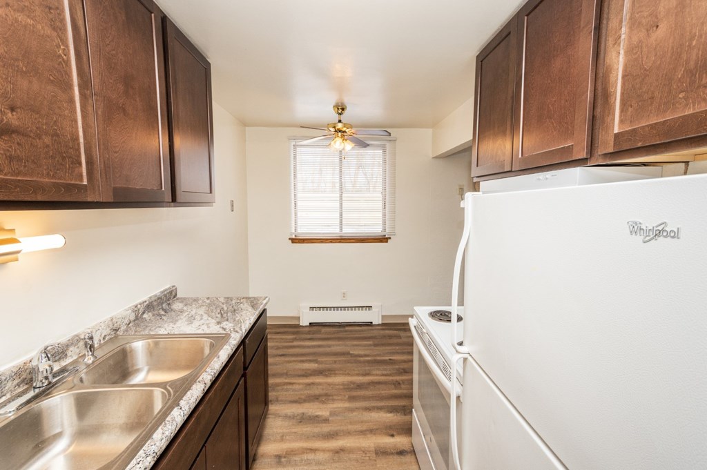 A kitchen with a white fridge and wooden cabinets.