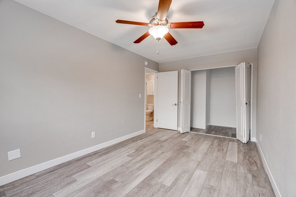 A room with a ceiling fan and a wooden floor.