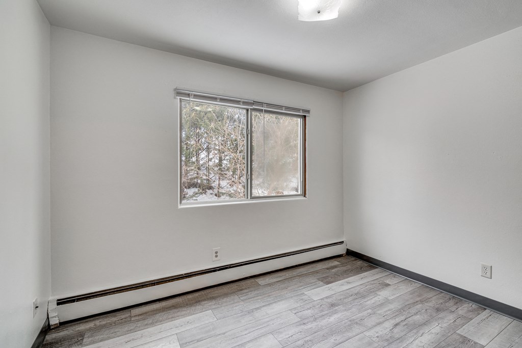 A room with a window and a wooden floor.
