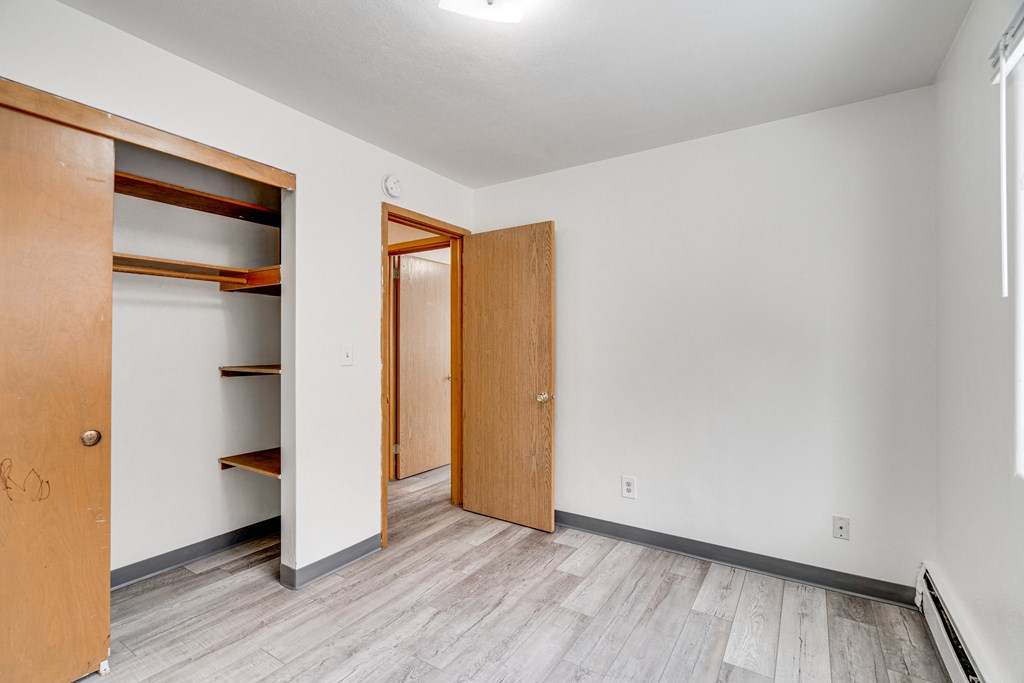 A room with a white wall and a brown door.