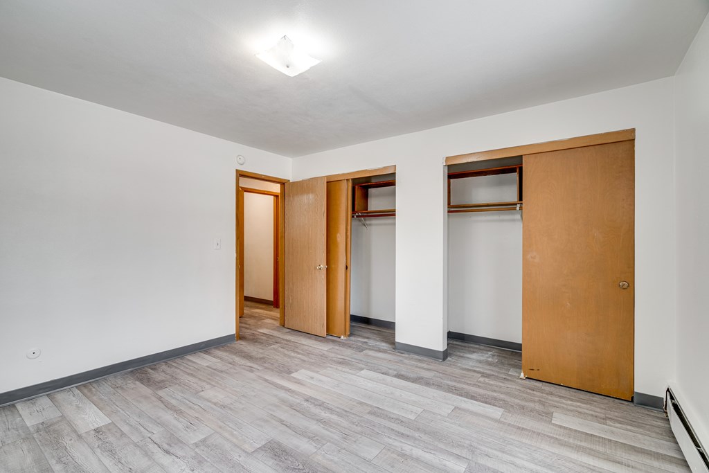 A room with a grey floor and white walls with three wooden doors.