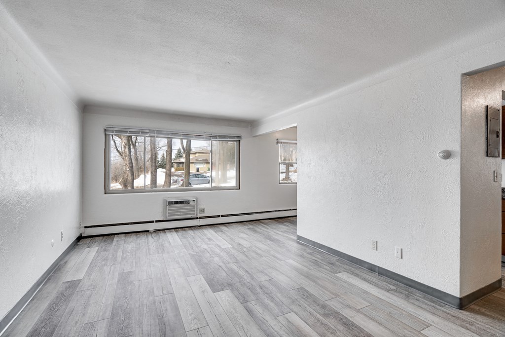 A room with a window and a wooden floor.