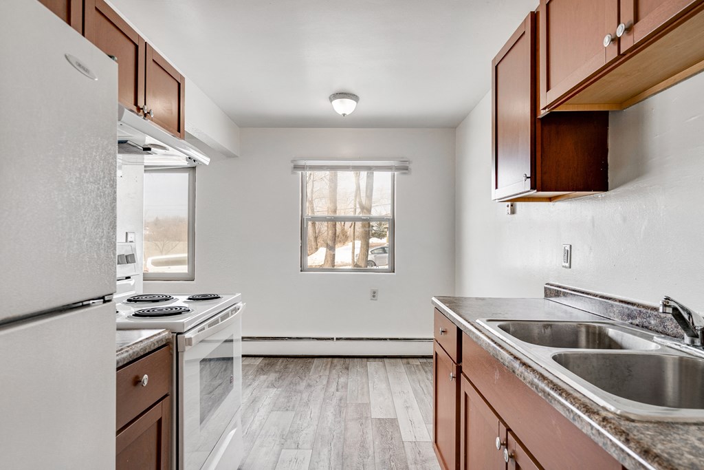 A kitchen with a white fridge, stove, and sink.