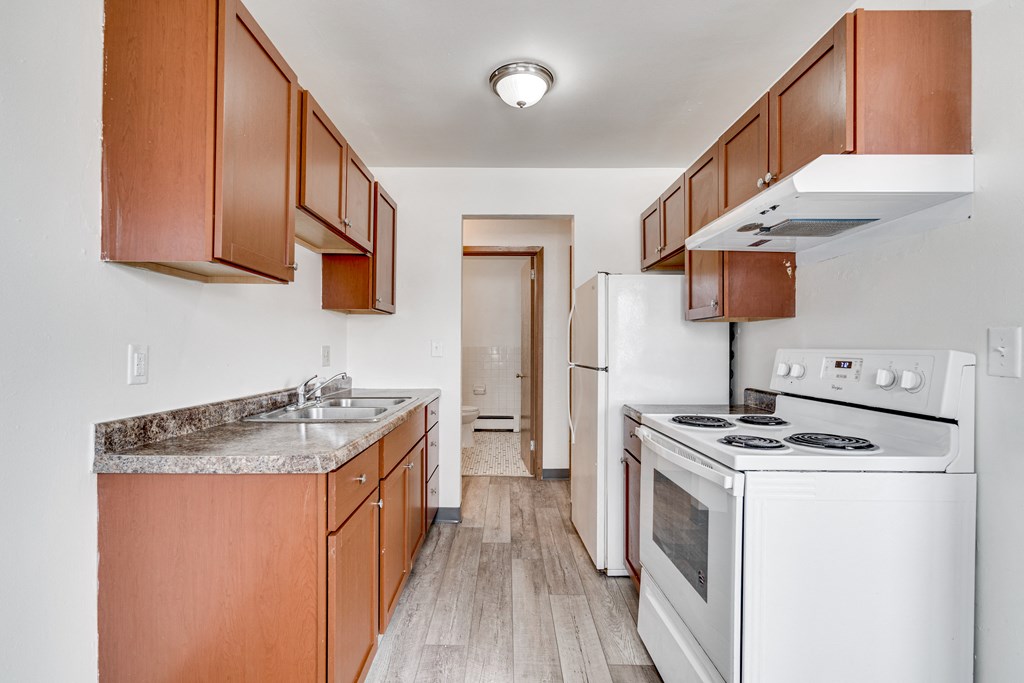 A kitchen with white appliances and wooden cabinets.