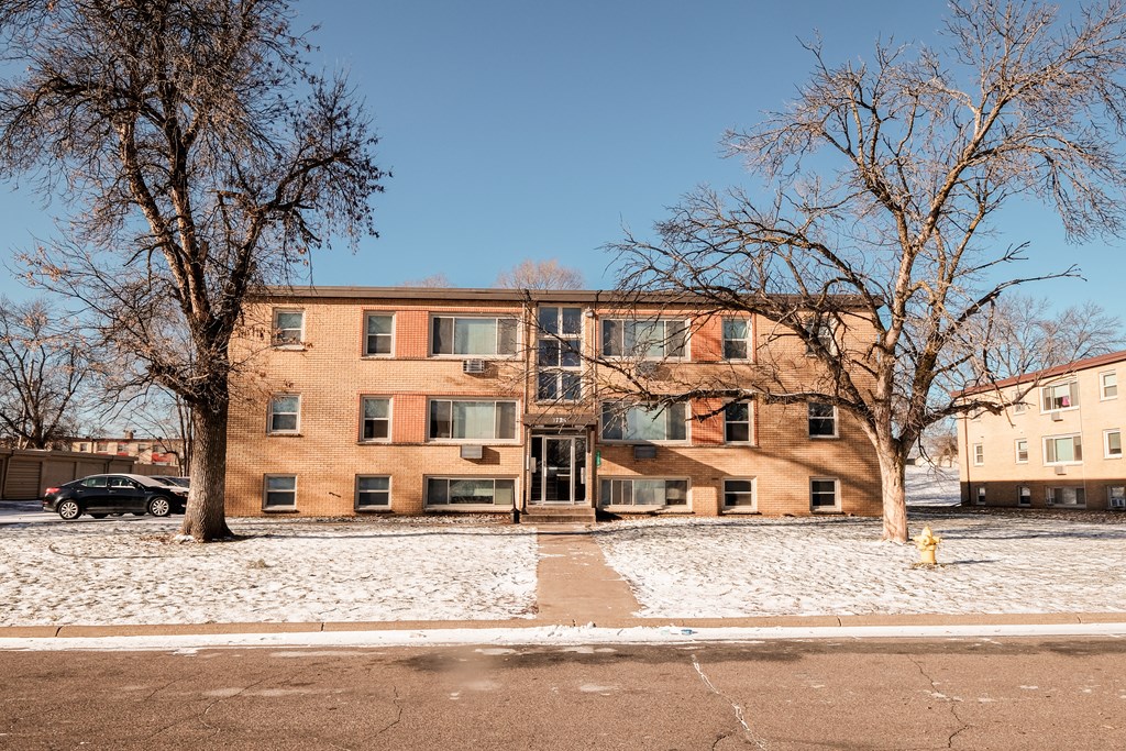 Apartment building with snow on the ground and bare trees.