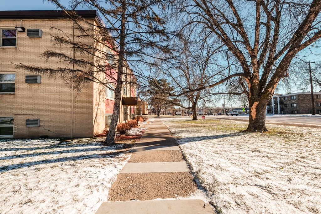 A snow-covered sidewalk leads to a brick building.