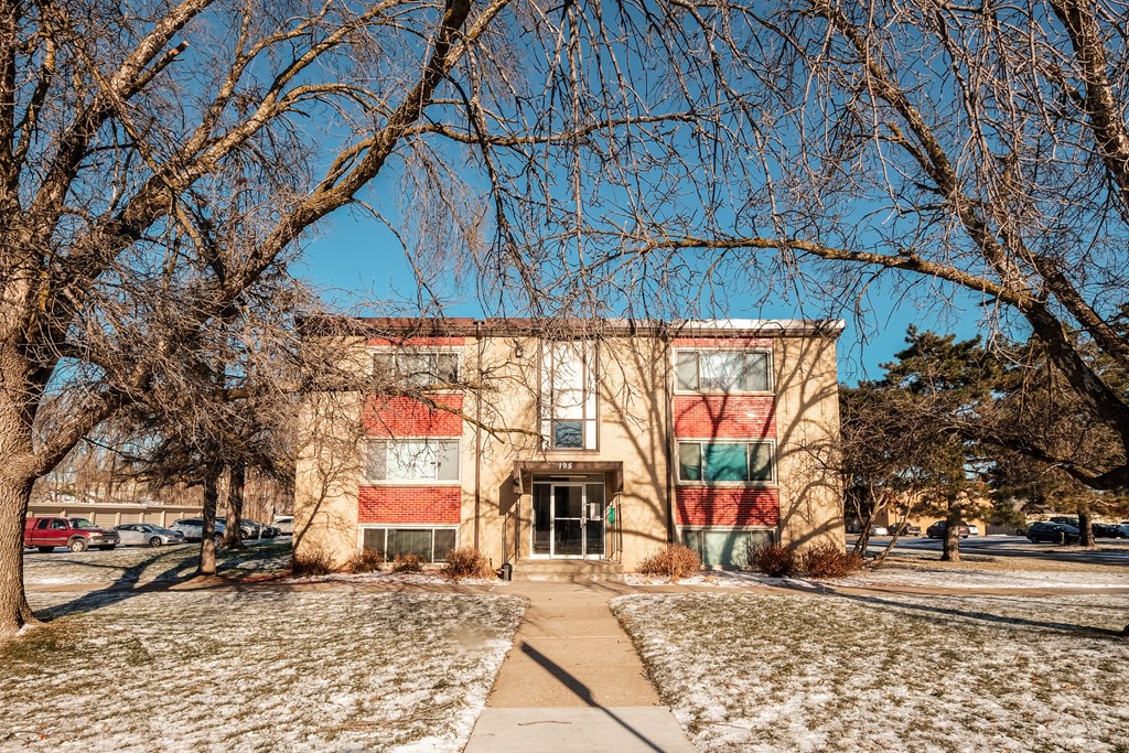 A building with a red and green striped wall is surrounded by bare trees.
