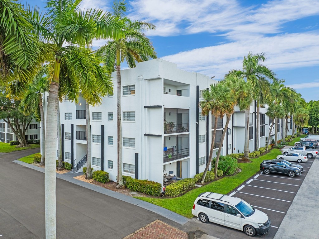 A white apartment building with a parking lot in front of it.