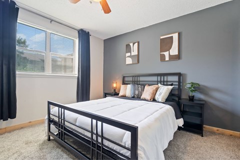 A bedroom with a bed, nightstand, and a ceiling fan.