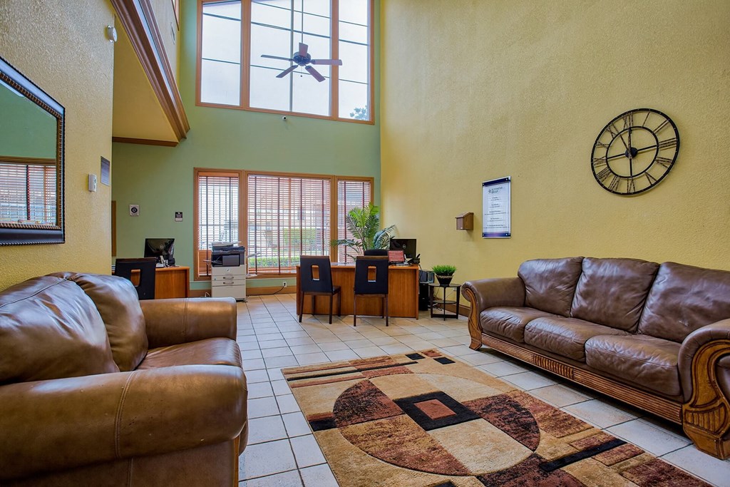 A living room with a brown leather couch and a rug with a circular design.