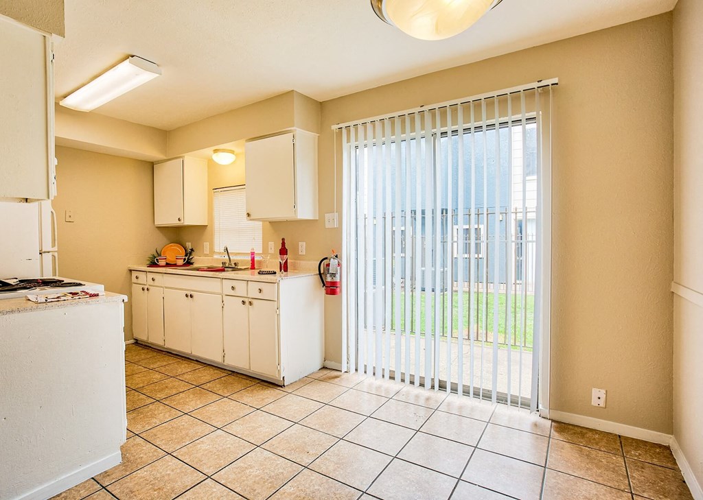 A kitchen with white cabinets and a tiled floor.