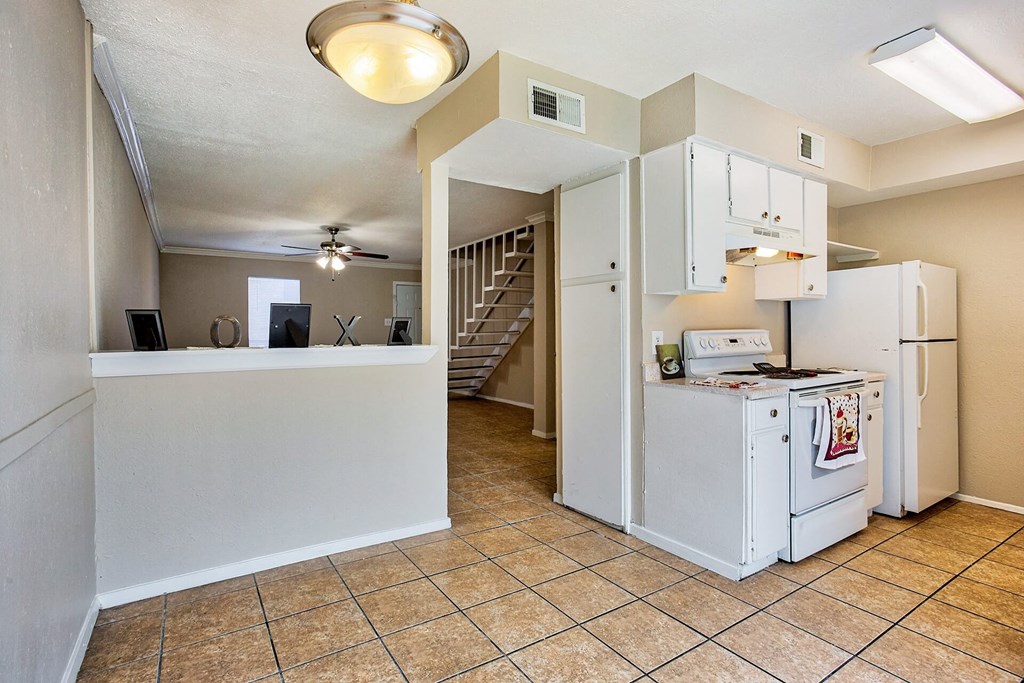 A kitchen area with a white fridge and a white counter.