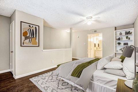 A bedroom with a bed, a painting on the wall, and a rug on the floor.