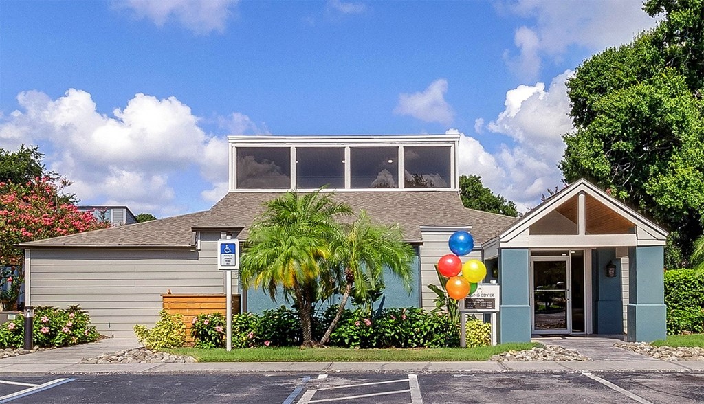 A small building with a blue door and windows is surrounded by a parking lot.