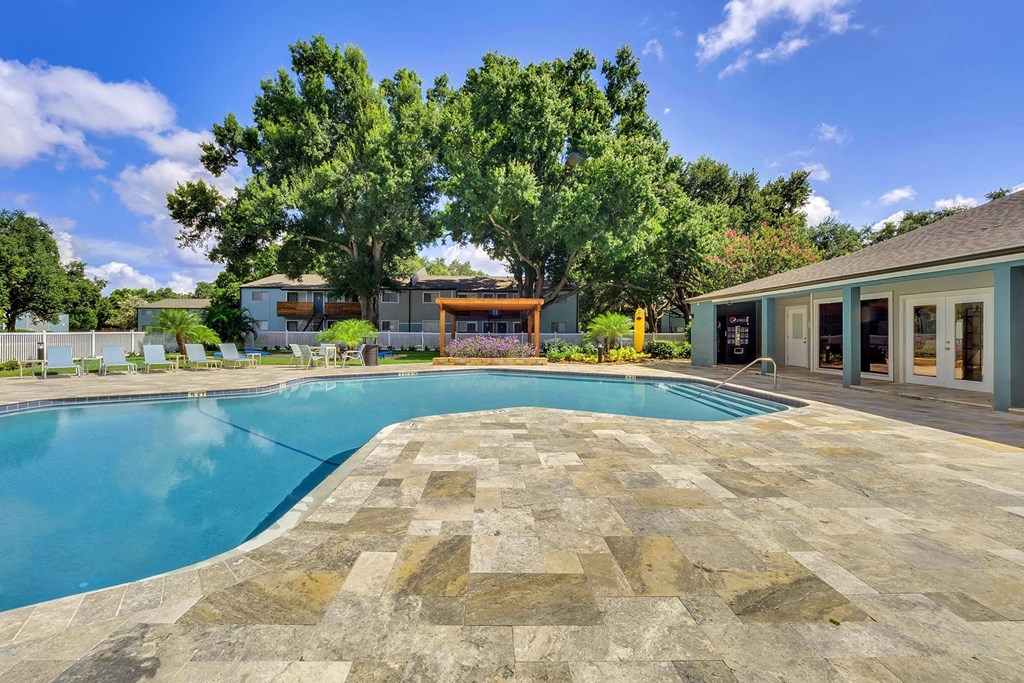A large swimming pool surrounded by a stone patio and a wooden deck.